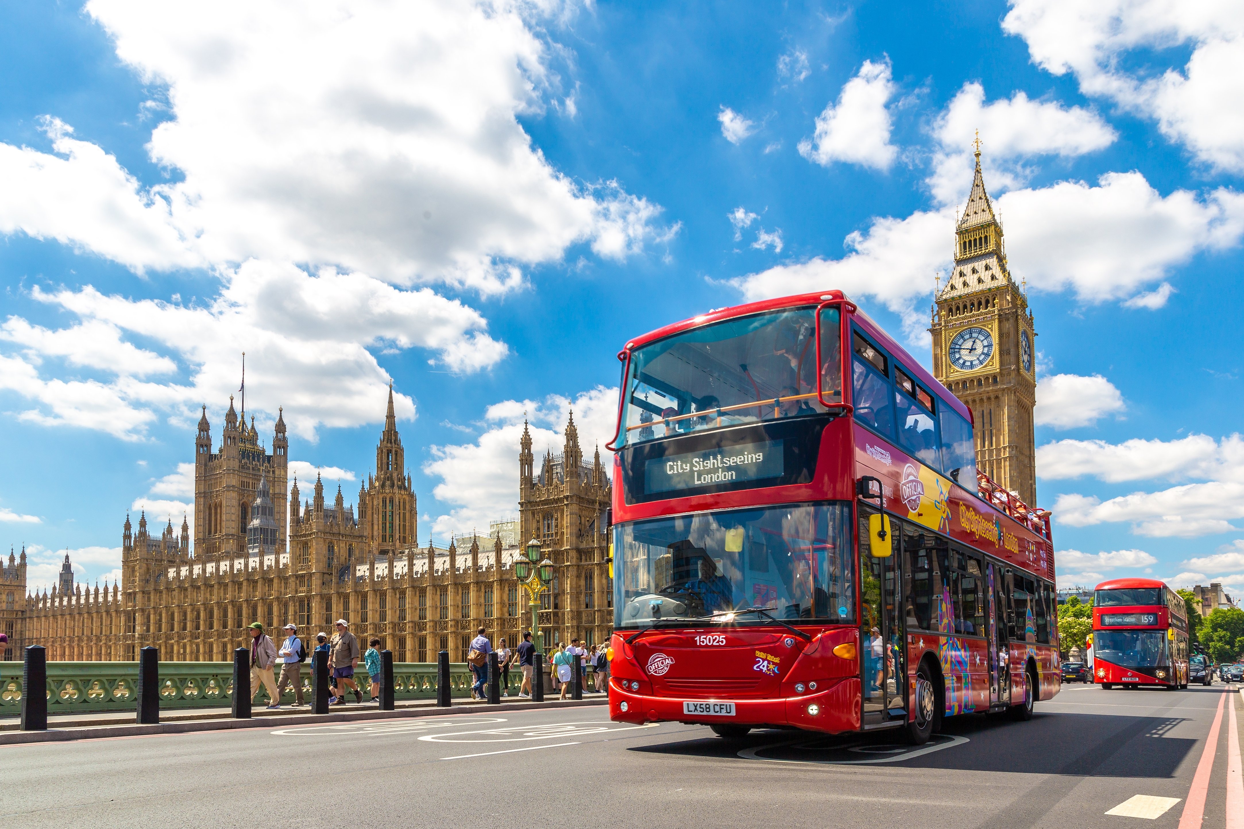 Red open top bus tour in front of Westminster Abbey