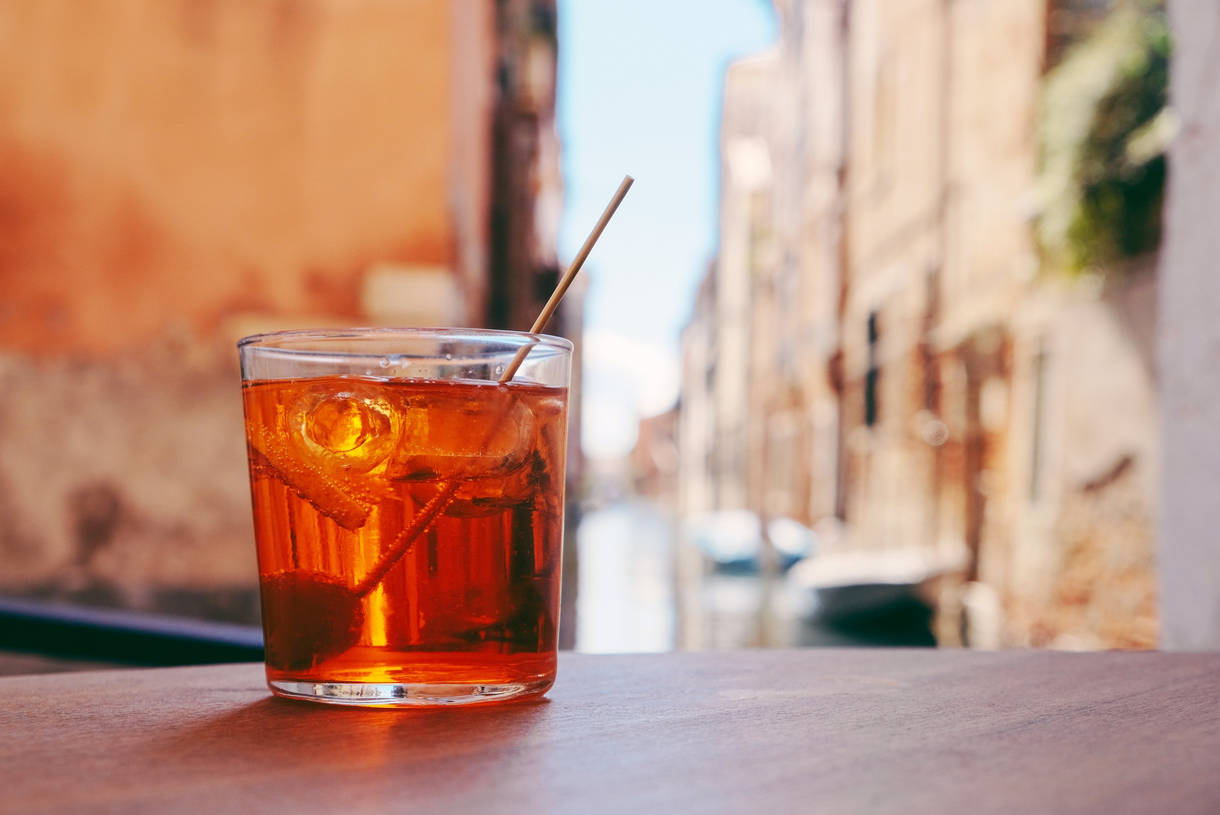 Orange cocktail with a backdrop of an Italian town