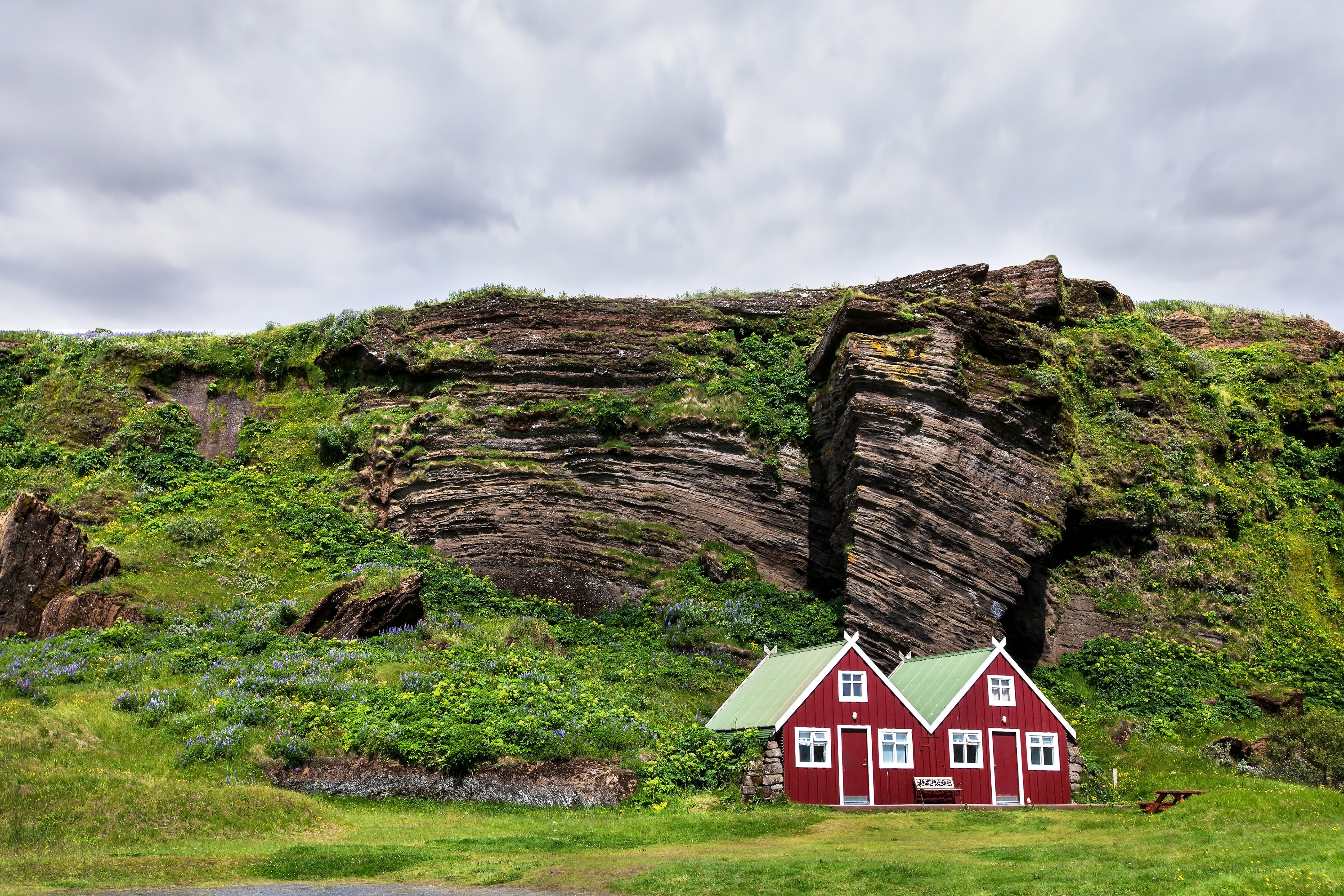 Red traditional houses in Iceland backed by mossy cliffs