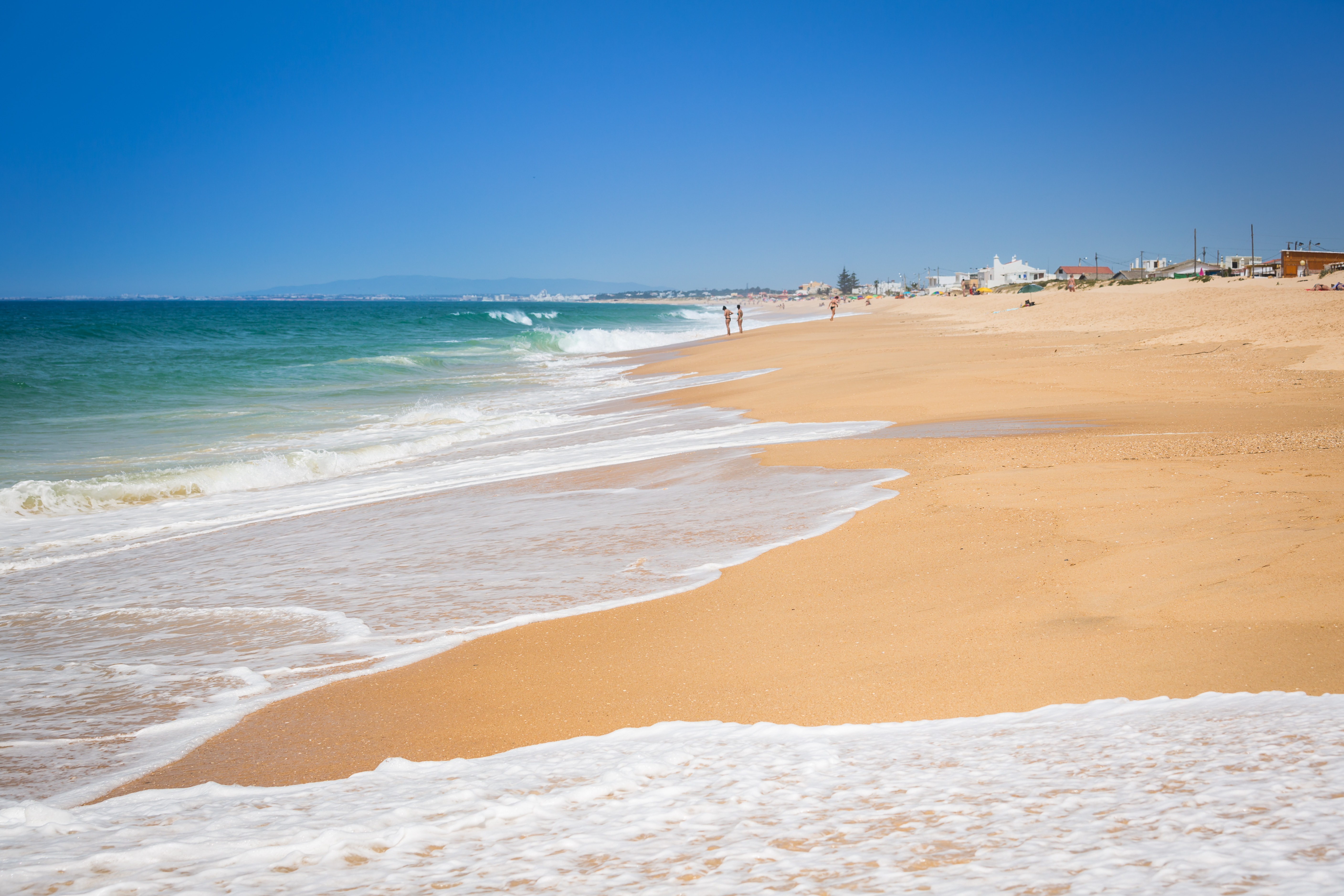 blue sea lapping onto golden beach in Faro, Algarve, Portugal