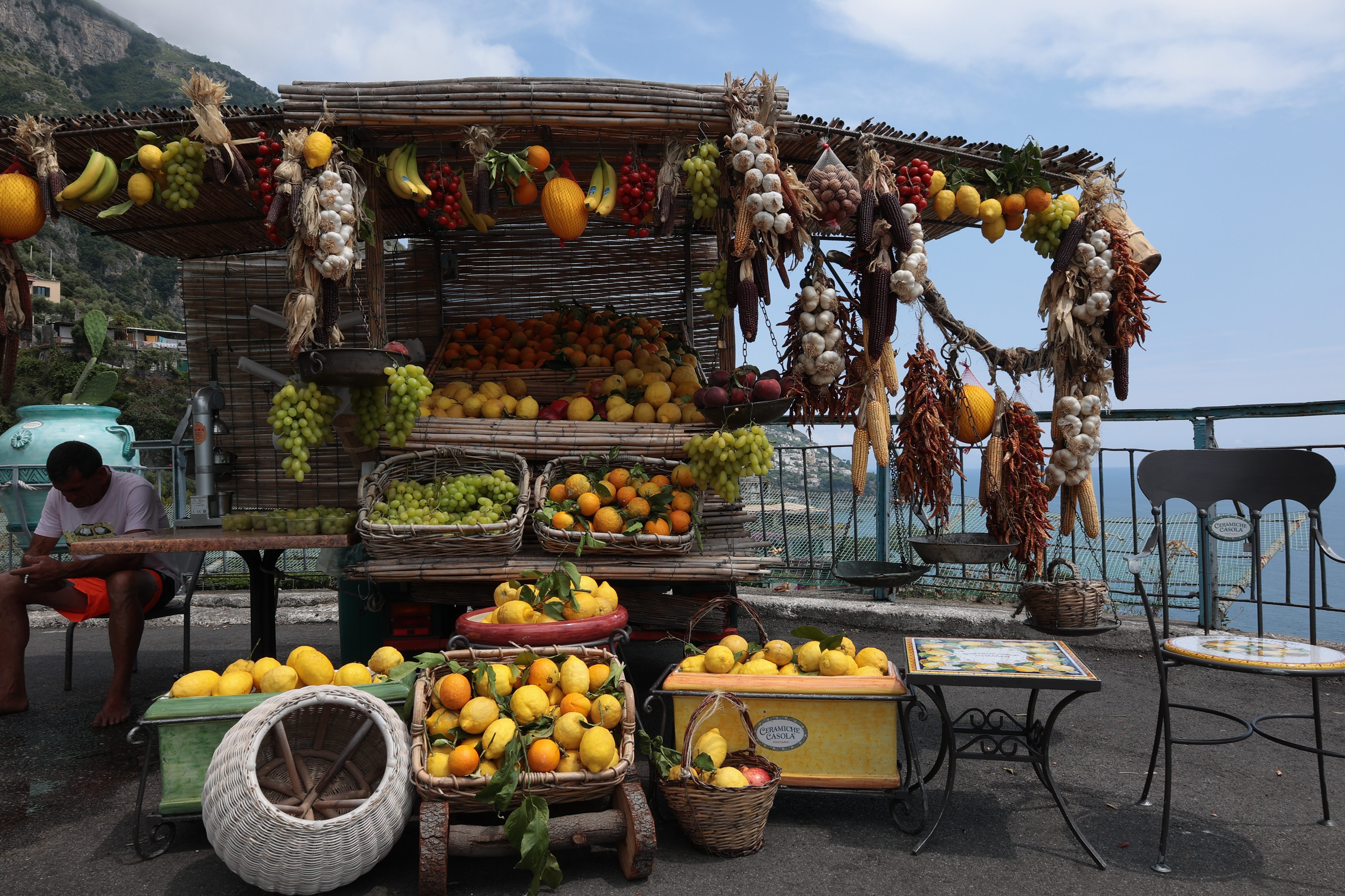 Fruit stand with grapes, oranges, bananas, onion and the blue sky in the background in Amalfi, Italy